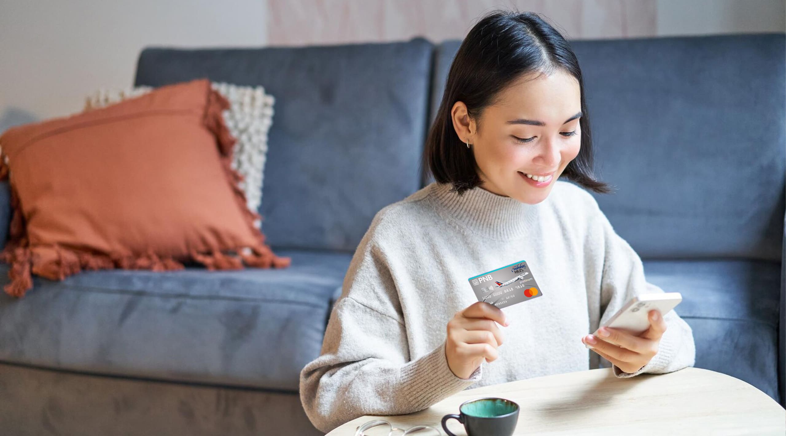 A woman holding a PNB-PAL Mabuhay Miles Platinum Mastercard in her living room