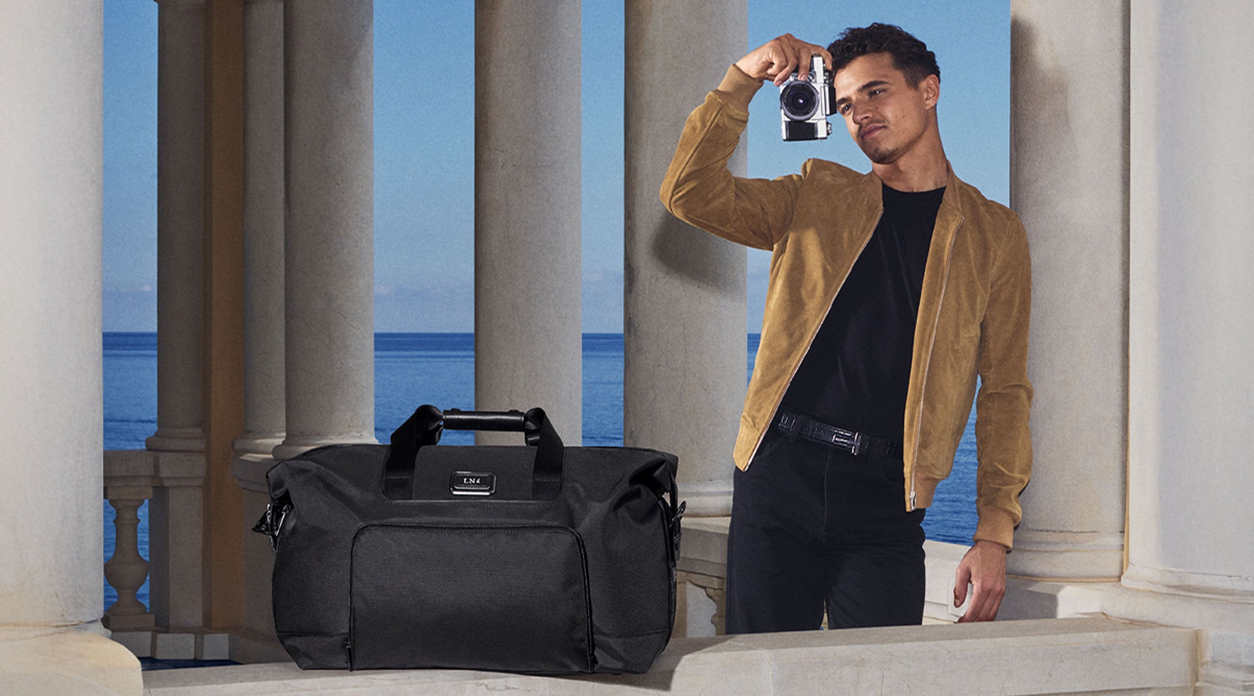 F1 McLaren Driver and longtime TUMI Global Ambassador Lando Norris with the TUMI Turin handbag at this side